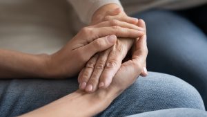 Junge Hände halten eine ältere Hand mit Achtsamer Berührung